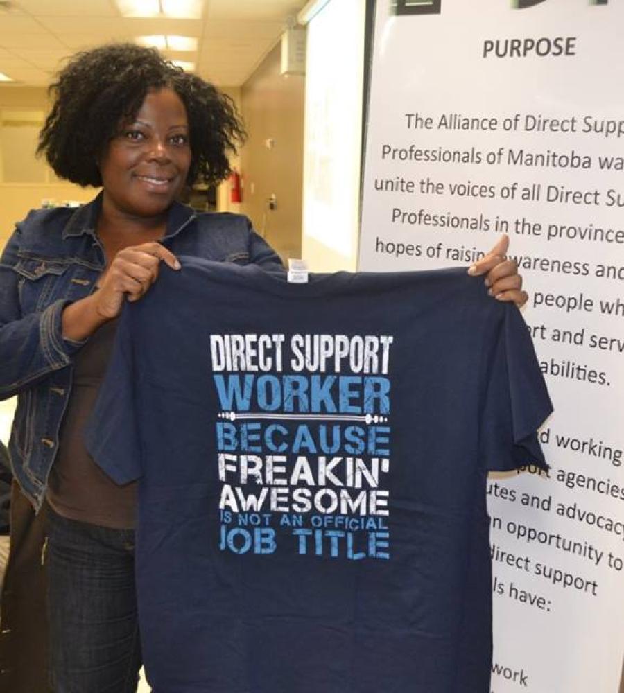 photo of a woman holding a shirt that says "direct support worker, because freakin' awesome is not an official job title"