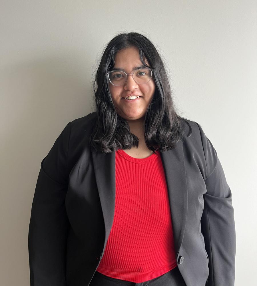 photo of Harsimran smiling, she is wearing a red shirt with a black blazer