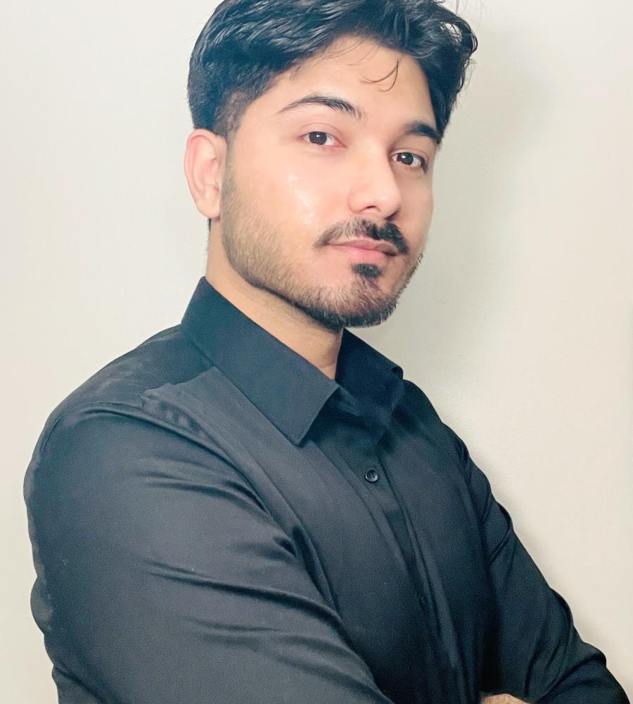 Photo of Kapil with his arms crossed smirking at the camera, wearing a black button down shirt., Kapil Ghirmire (he/him), Director